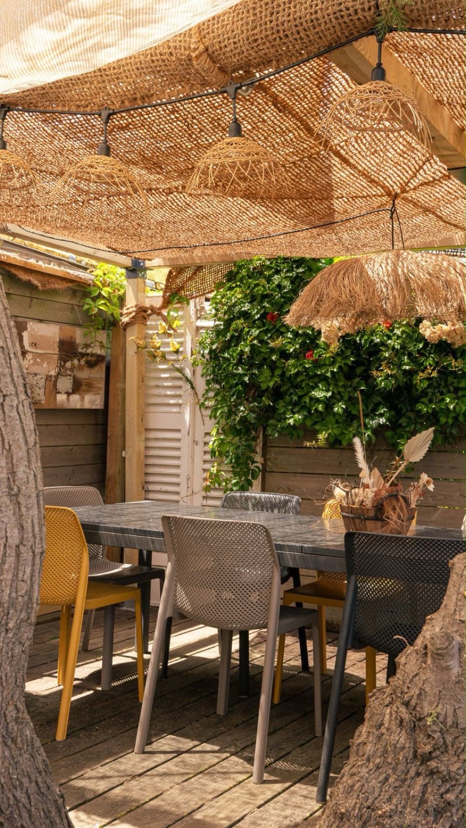 Terrasse ombragée en rotin sous les arbres, à La Paillote